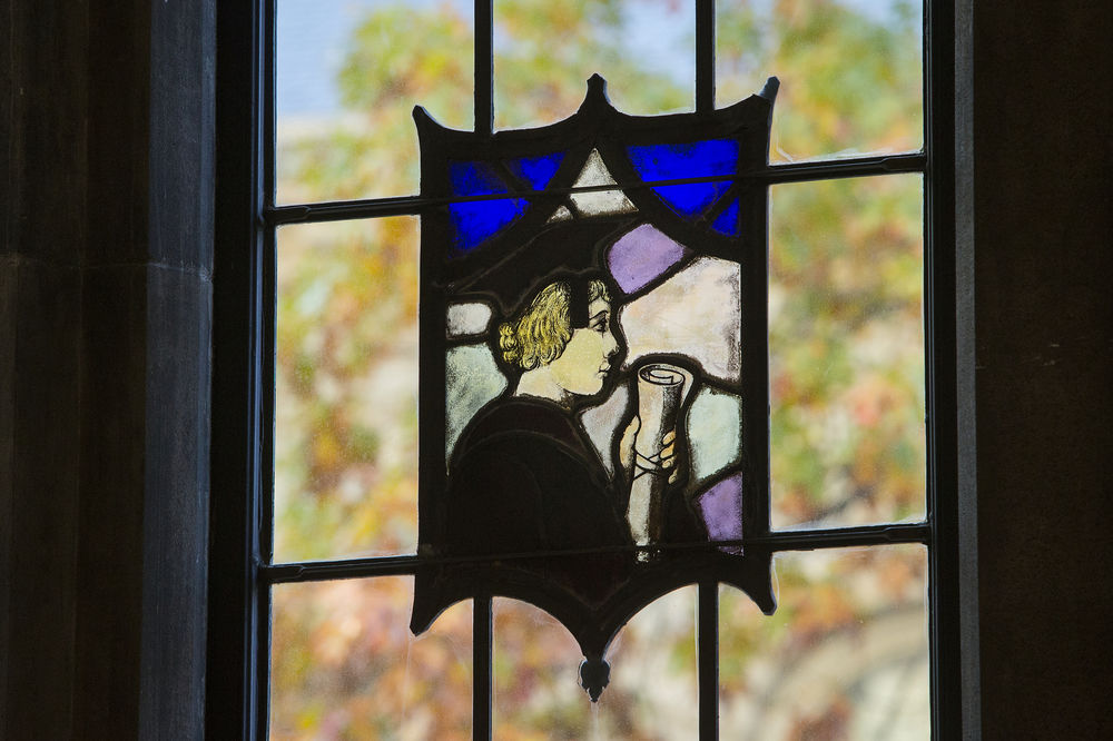 A stained-glass window featuring a graduate holding a diploma.